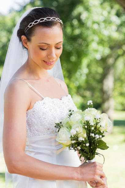 istock Shy bride holding flower bouquet in garden 691218152