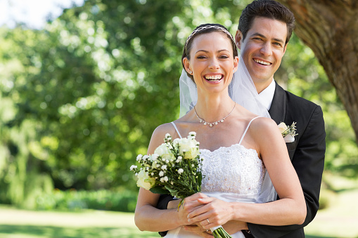Portrait of newly wed couple with flower bouquet in park