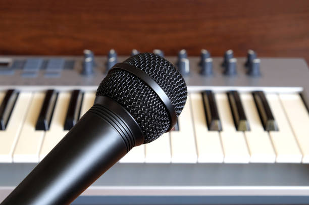 istock Black vocal microphone closeup against electronic synthesizer keyboard 691228990