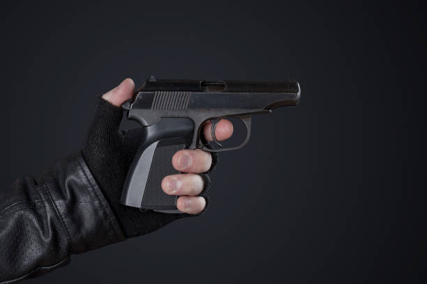 istock Gangster with a gun in his hand and a leather jacket on a dark background 691235722