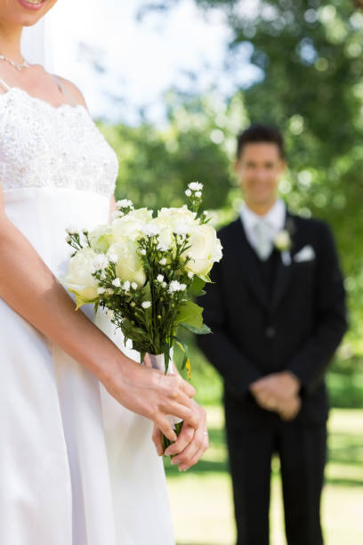 istock Bride holding bouquet with groom standing in background 691245044