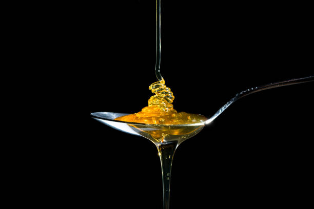 Honey on spoon on black background