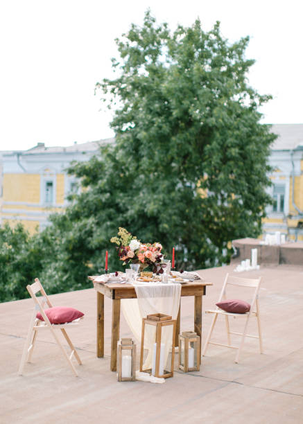 istock Wedding decor. Perfectly decorated holiday table for two with beautiful flower composition of fresh flowers in a vintage vase, red candles, thinly cut jamon, green olives and fresh bread 691262120