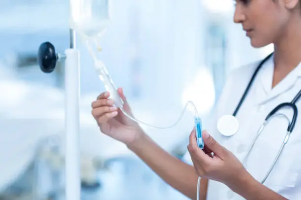 Nurse connecting an intravenous drip in hospital room