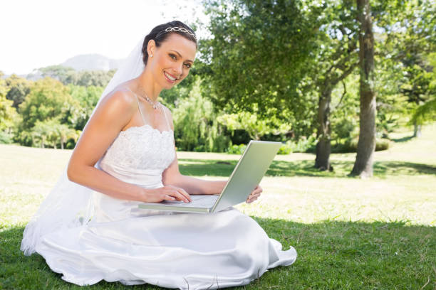 istock Beautiful bride using laptop in garden 691273268