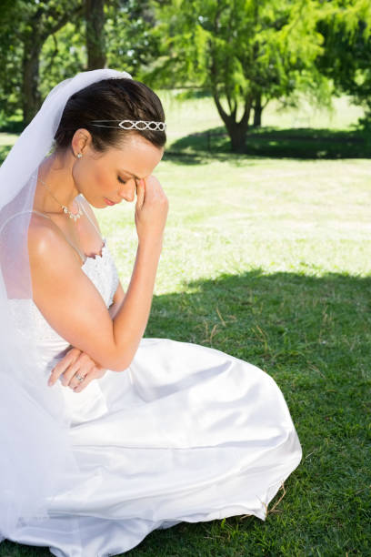 istock Female bride sitting on grass in park 691275968