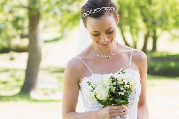 istock Bride looking at bouquet in garden 691276140
