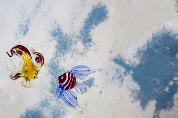 Transparent glass fishes on a blue white background