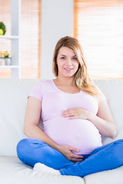 istock Pregnant woman looking at camera with hands on belly 691282928