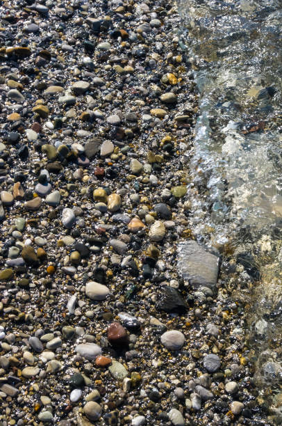 istock sea pebble beach with multicoloured stones, waves with foam 691291366