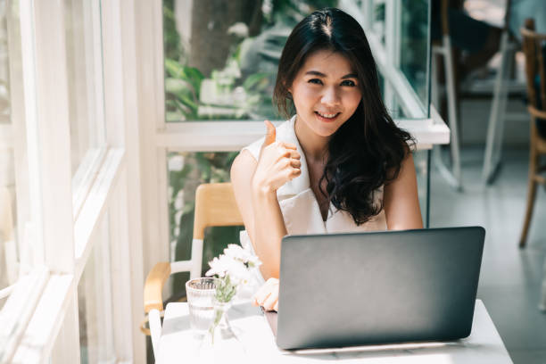 istock Happy Asian woman showing thumb up while working with laptop 691294140