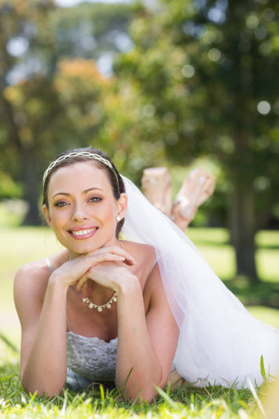 istock Beautiful bride lying on grass in park 691294412