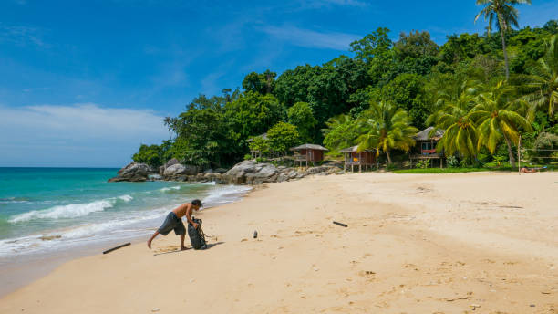 An unidentified man leaves backpack on pristine tropical beach. Perhentian Islands (Mira Beach): An unidentified man leaves backpack on pristine tropical beach. palau beach stock pictures, royalty-free photos & images