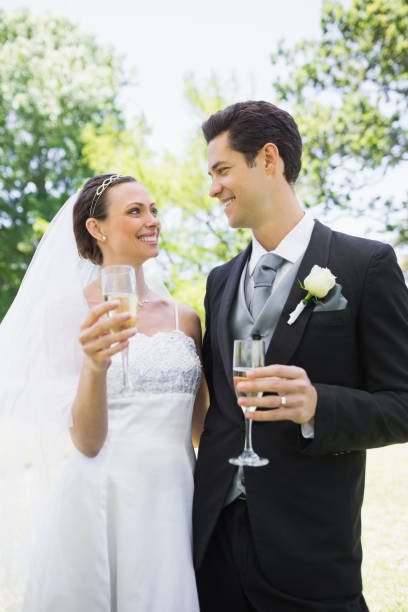 istock Romantic bride and groom having champagne in park 691294992