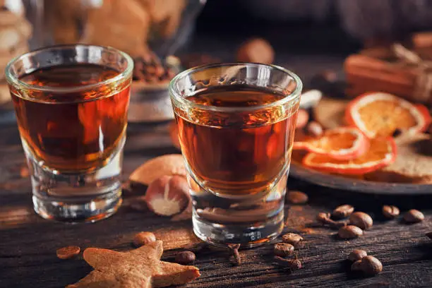 Whiskey or liqueur, cookies, spices and decorations on wooden background. Seasonal holidays concept.