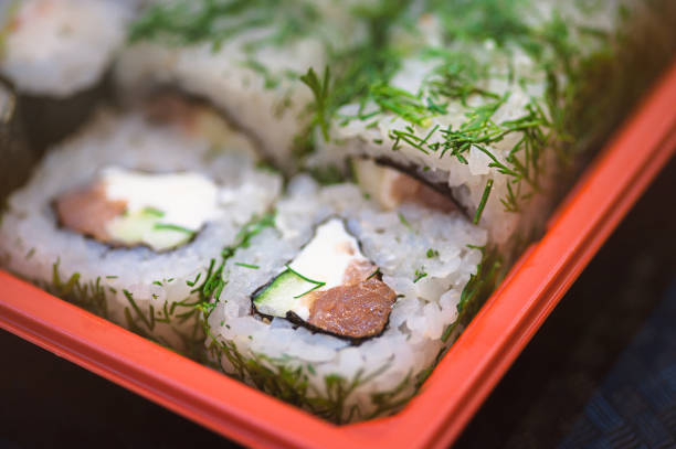 Set salmon rolls in a plastic plate on a black background Top view of bento to-go plastic box, mixed nigiri and assorted sushi roll in lunch box place on wooden background. васаби stock pictures, royalty-free photos & images