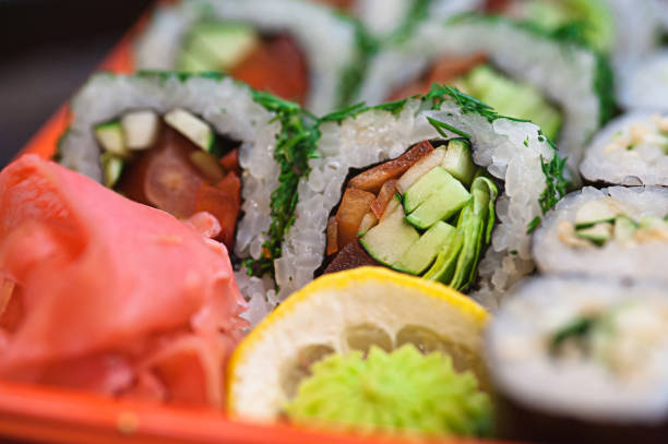 Large set of japanese rolls on a black plastic plate Top view of bento to-go plastic box, mixed nigiri and assorted sushi roll in lunch box place on wooden background. васаби stock pictures, royalty-free photos & images