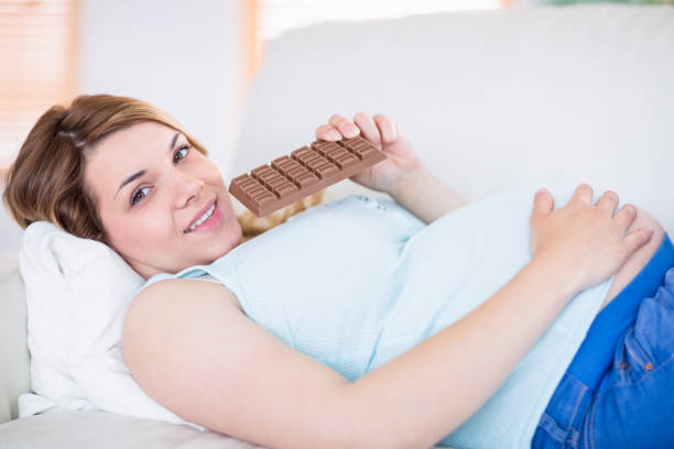 istock Pregnant woman looking at camera and eating chocolate 691301558