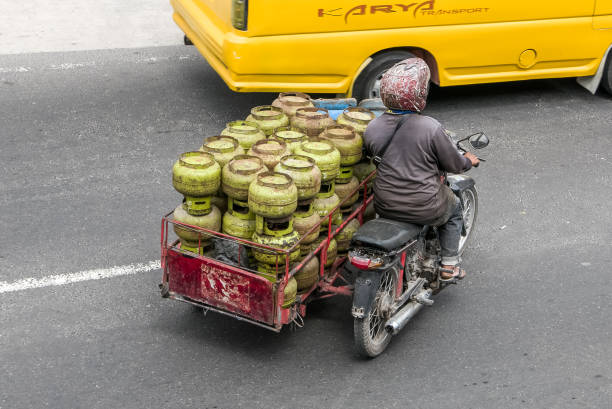 A biker transports the gas bottles on busy street in Sumatra. stock photo