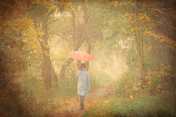 photo of beautiful young woman holding umbrella and walking in the woods on the wonderful trees background