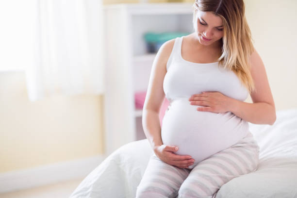 istock Pregnant woman looking at her belly 691325832
