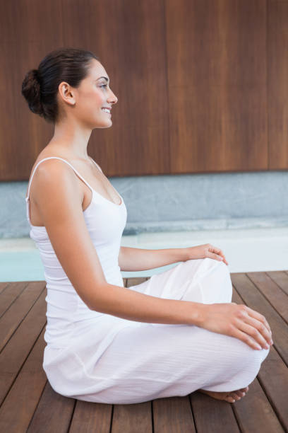 istock Content brunette in white sitting in lotus pose 691326880