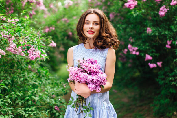 young girl stand at park background with bouquet of flowers - sensuality walking women beautiful imagens e fotografias de stock