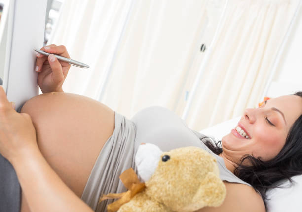 istock Pregnant woman writing on clipboard 691337852