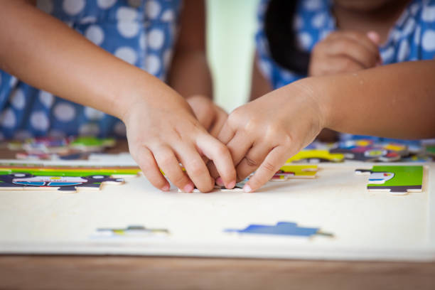 istock Two children hands helping and trying to connect jigsaw puzzle piece to learn to find solution 691338214