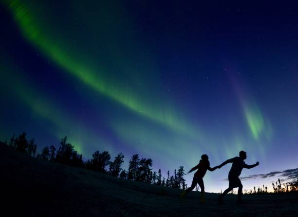 Magic run. A young couple running under the aurora borealis in Canada's great north. great slave lake stock pictures, royalty-free photos & images