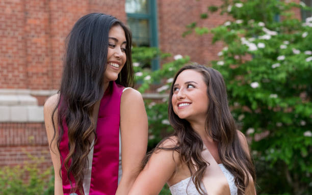 College Graduation Photo on University Campus Two attractive female college students and best friends pose for a photo together on a university campus during the Spring in Oregon. sorority photos stock pictures, royalty-free photos & images