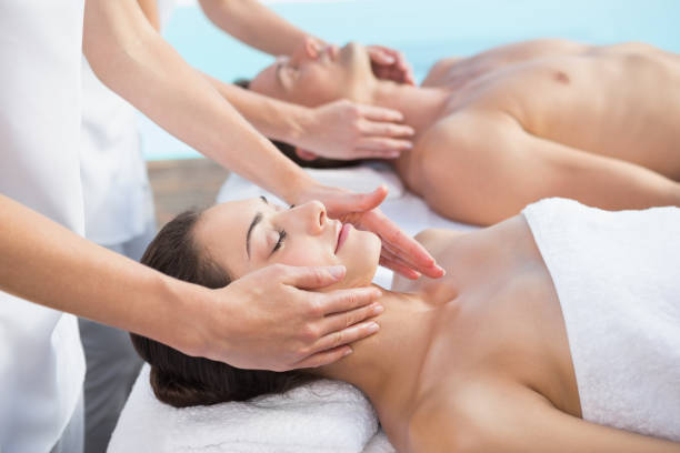 coppia tranquilla che si gode il massaggio delle coppie a bordo piscina - head massage massaging beauty treatment massage therapist foto e immagini stock