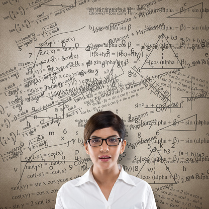 Portrait of businesswoman with mathematical equation on wall