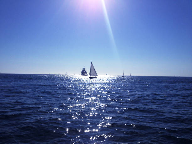 istock A single sail boat catches the sunlight, framed across the water. 691371064