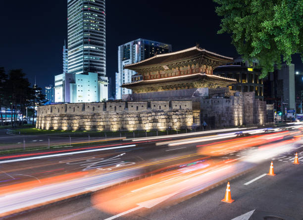 Traffic, captured with blurred motion, rushes around the Dongdaemun gate at night in Seoul, South Korea capital city. The gate was part of the Seoul city wall surrounding the city.