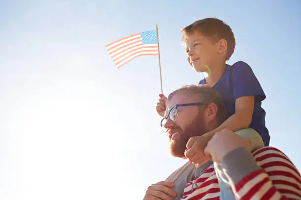 Patriotic family with American flag visiting parade devoted to Independence Day