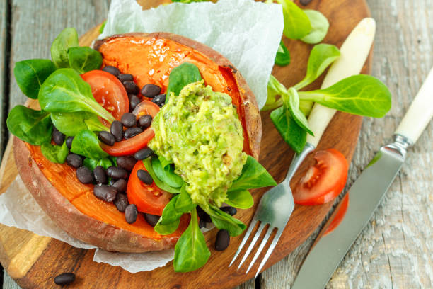 Baked whole sweet potato with guacamole and black beans