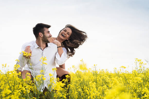 istock Cheerful couple having fun while piggybacking in yellow flowers. 691417808
