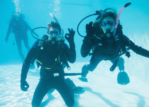 istock Friends on scuba training submerged in swimming pool two looking to camera 691419006