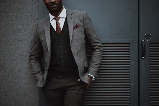 confident stylish african american businessman posing outdoors at wall