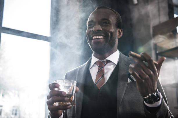위스키와 담배 시가 유리를 들고 웃는 아프리카계 미국인 실업가 - smoking man 뉴스 사진 이미지
