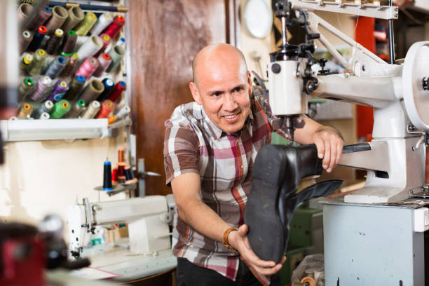 istock Mature workman sewing leather boots on stitch lathe 691437434