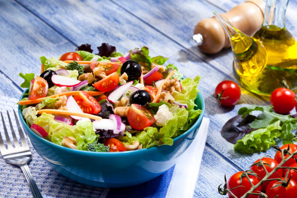 frischer salatteller auf blauen picknick-tisch - salat stock-fotos und bilder