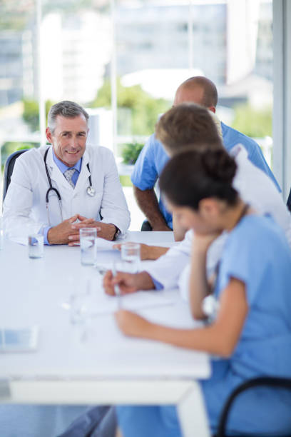 istock Happy doctor smiling at camera while his colleagues works 691452718