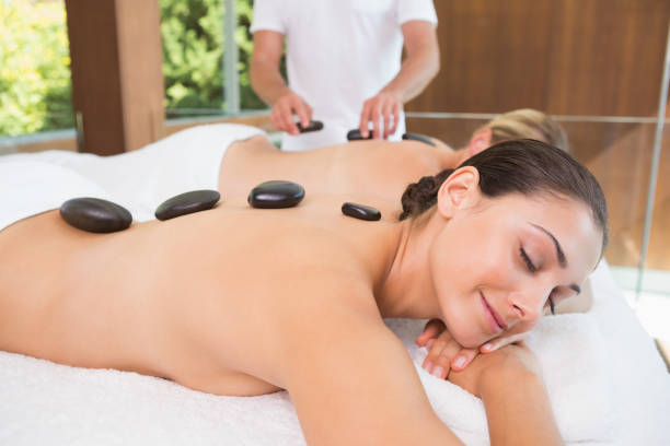 istock Happy friends lying on massage tables with hot stones on their backs 691455550