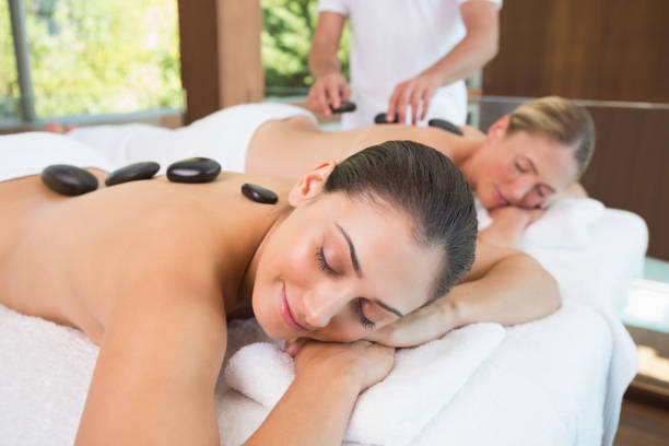 istock Calm friends lying on massage tables with hot stones on their backs 691455562