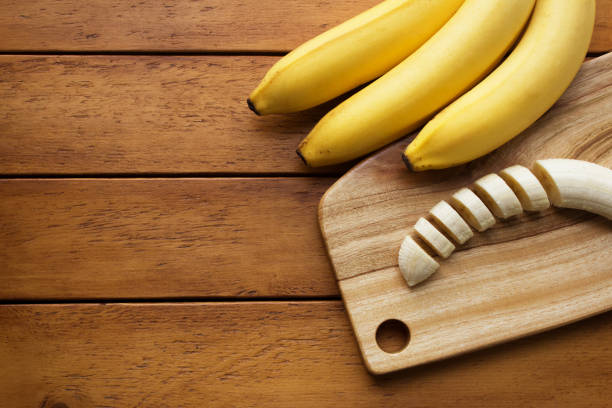 Yellow banana and cutting board on wooden table
