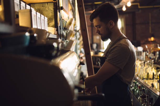 istock Young male barista preparing drink at coffee machine 691460444