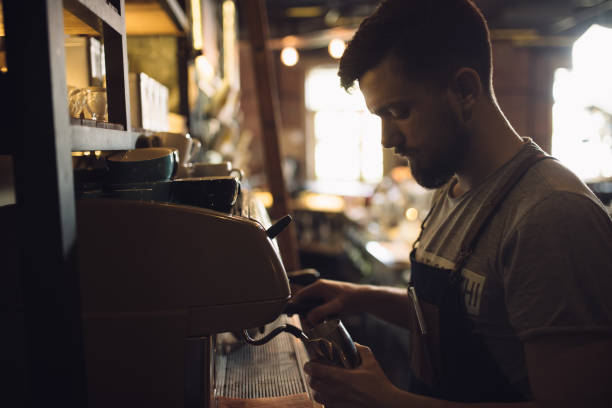 istock Young male barista preparing drink at coffee machine 691460454