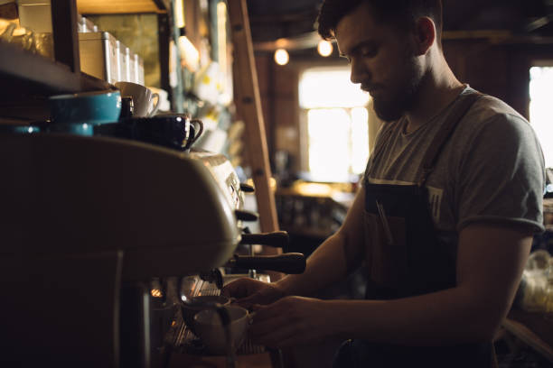 istock Young male barista preparing drink at coffee machine 691460520